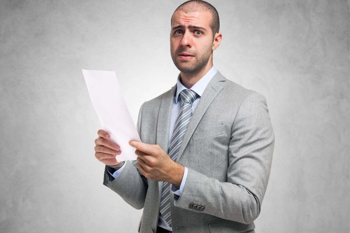 uomo preoccupato con un foglio in mano