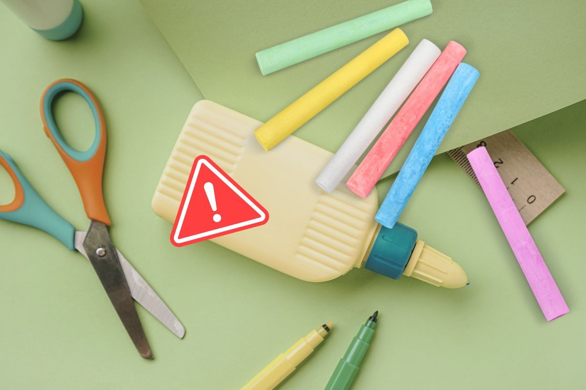 materiale scolastico, colla , gessetti, fogli e segnale di pericolo